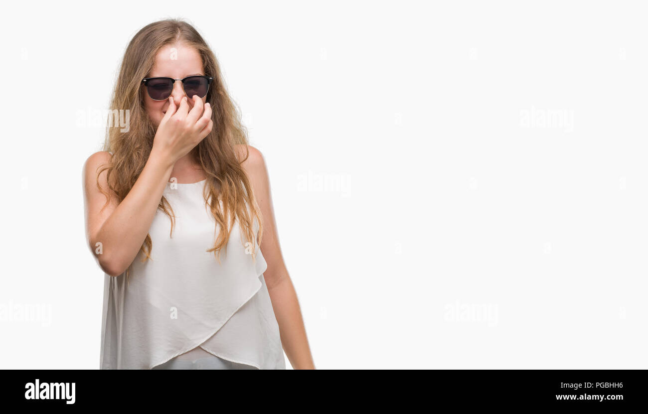 Giovane donna bionda indossando occhiali da sole annusare qualcosa di  maleodorante e disgustoso, intollerabile odore, trattenendo il respiro con  le dita sul naso. I cattivi odori con Foto stock - Alamy
