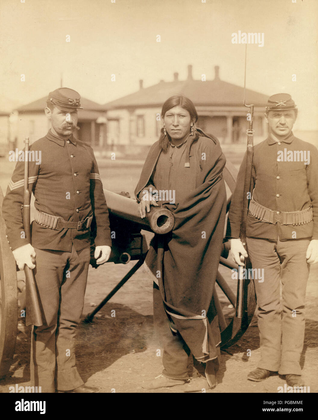 Molti cavalli, Oglala uomo e due soldati statunitensi in piedi di fronte a un cannone in un accampamento militare. Foto Stock