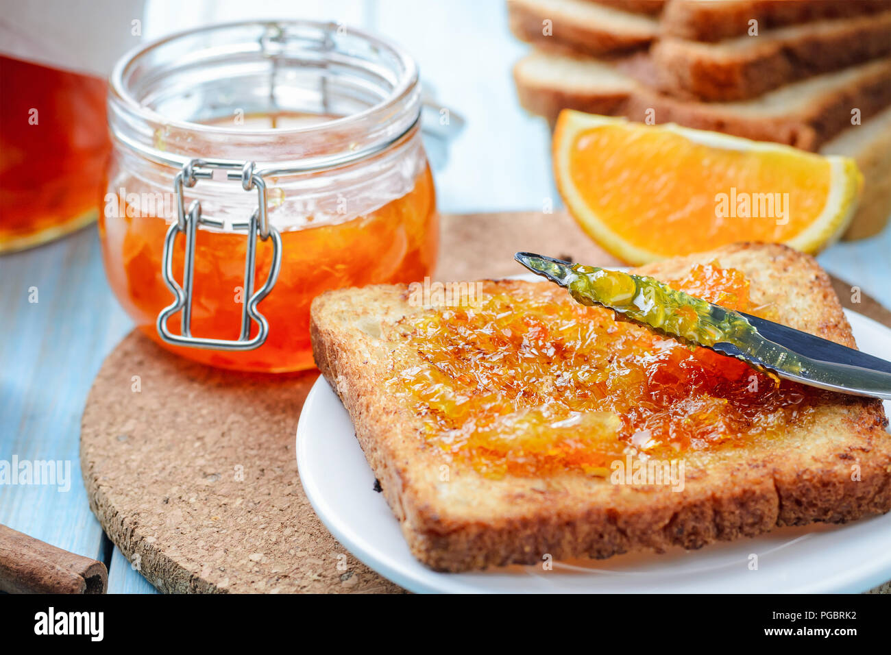 Fette di pane tostato con marmellata di arancio e il vasetto di vetro per la prima colazione Foto Stock