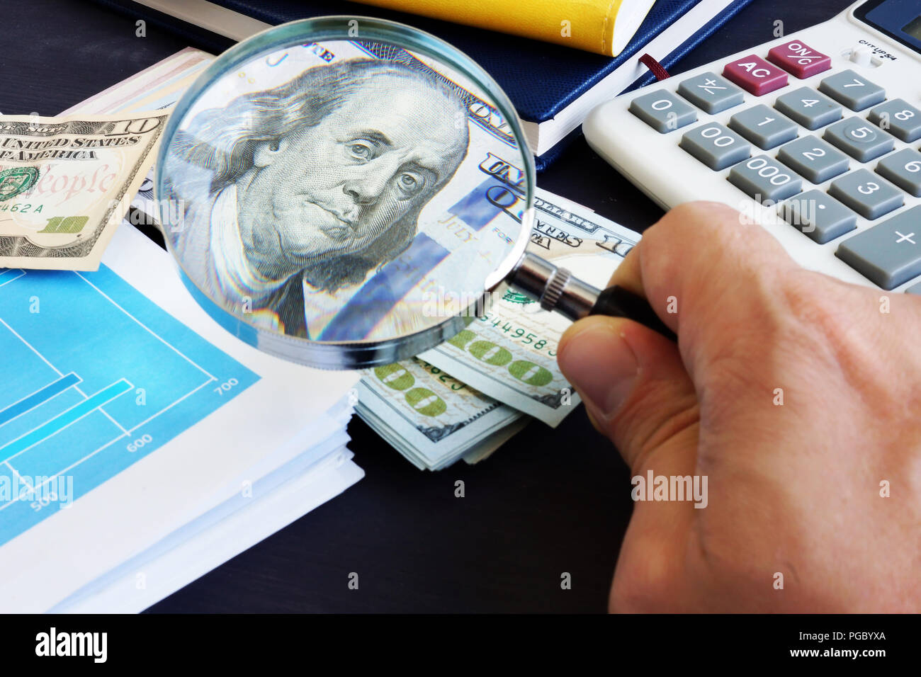 Uomo che guarda attraverso la lente di ingrandimento su una banconota del dollaro. Audit e ricerca finanziaria. Foto Stock