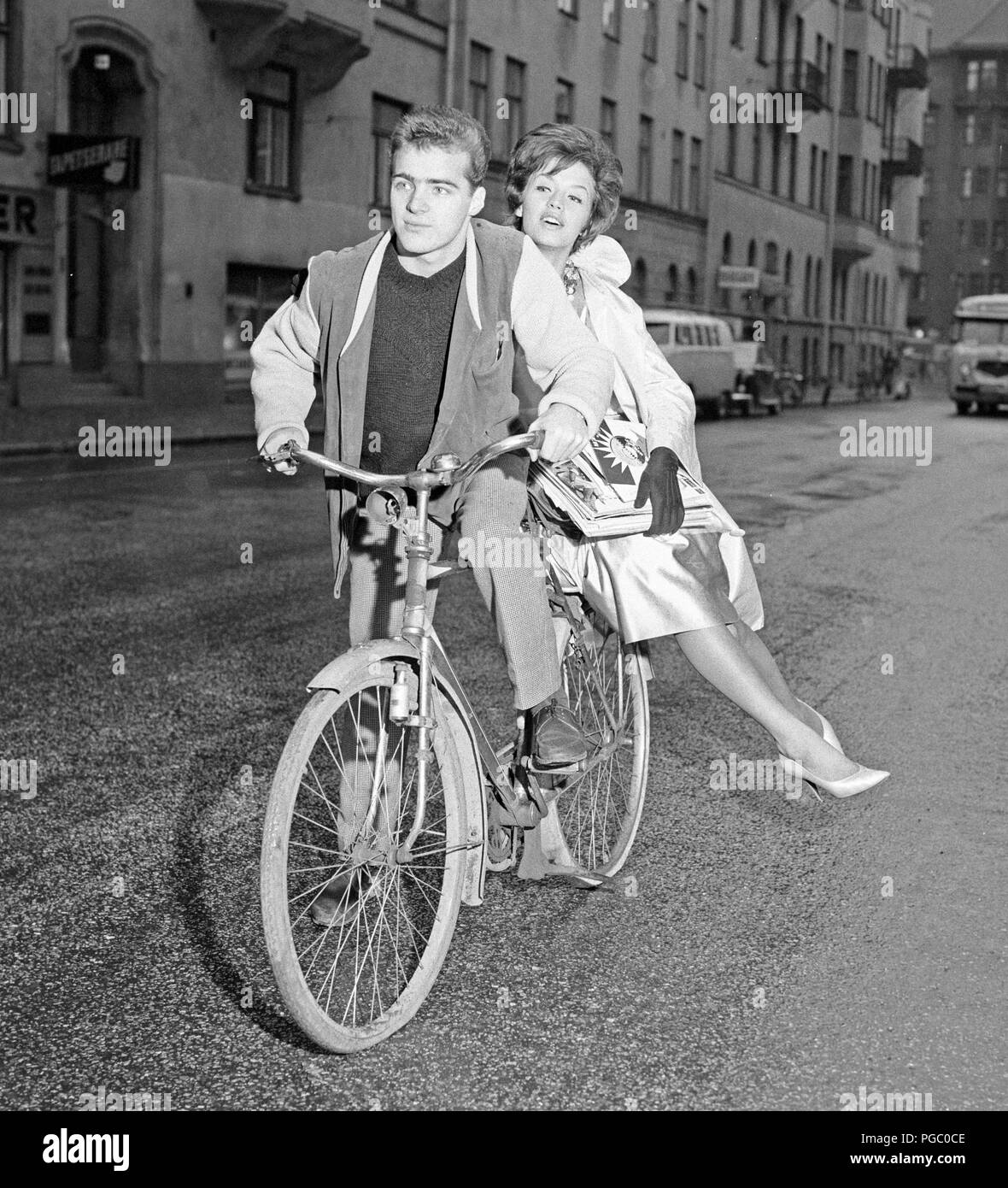 Anni sessanta ciclista. Un giovane uomo sulla sua bicicletta ha un elegante vestito donna seduta sulla cremagliera sulla ruota posteriore. Lei è la cantante svedese Lill-Babs Svensson. La Svezia 1961. Foto Kristoffersson CP83-5 Foto Stock