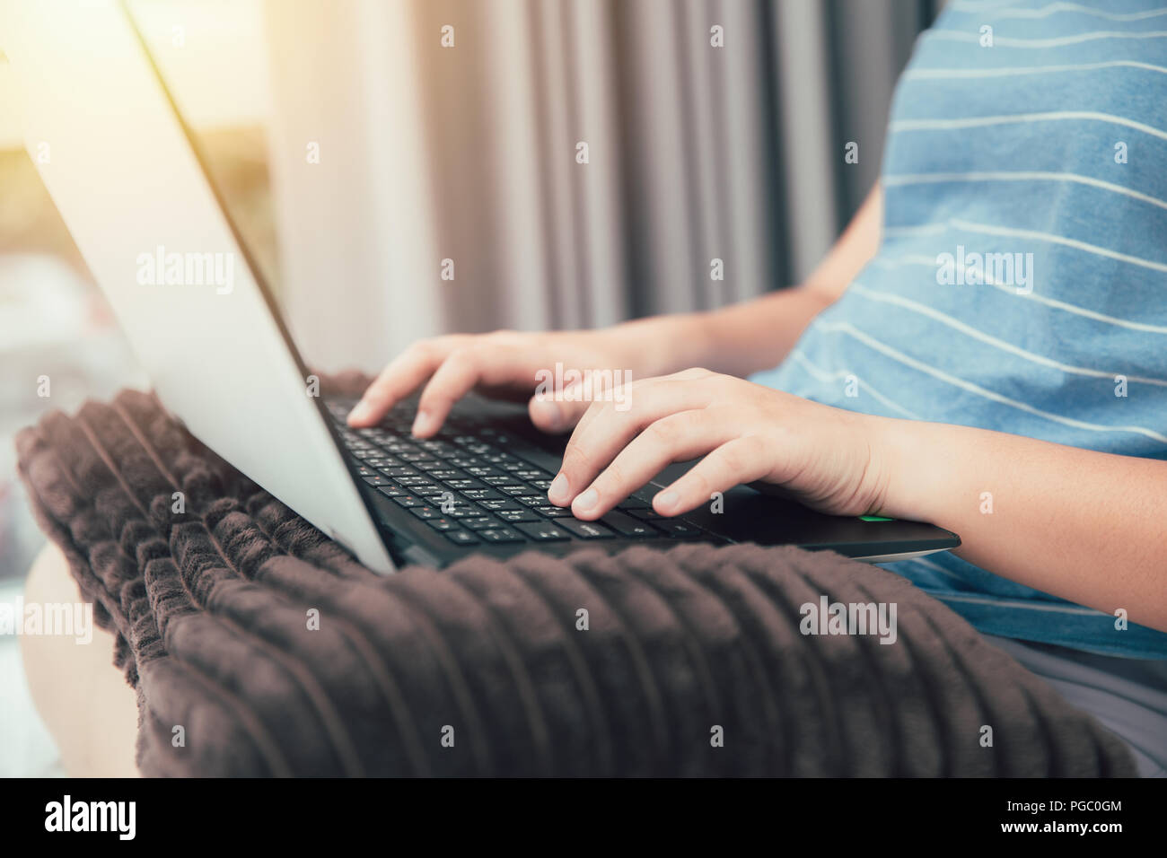 Casual imprenditrice mano a computer tastiera portatile posto sul cuscino di lavoro a casa camera da letto stile di vita. Foto Stock