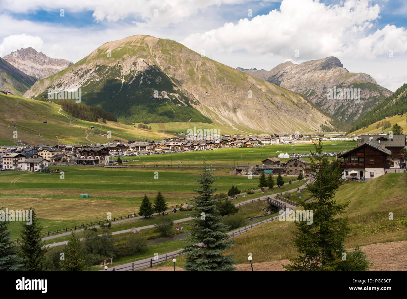 Scenic paesaggio alpino con città e chalet nelle alpi italiane a Livigno Lombardia incastonato in una valle al di sotto di alta alpine picchi di montagna Foto Stock