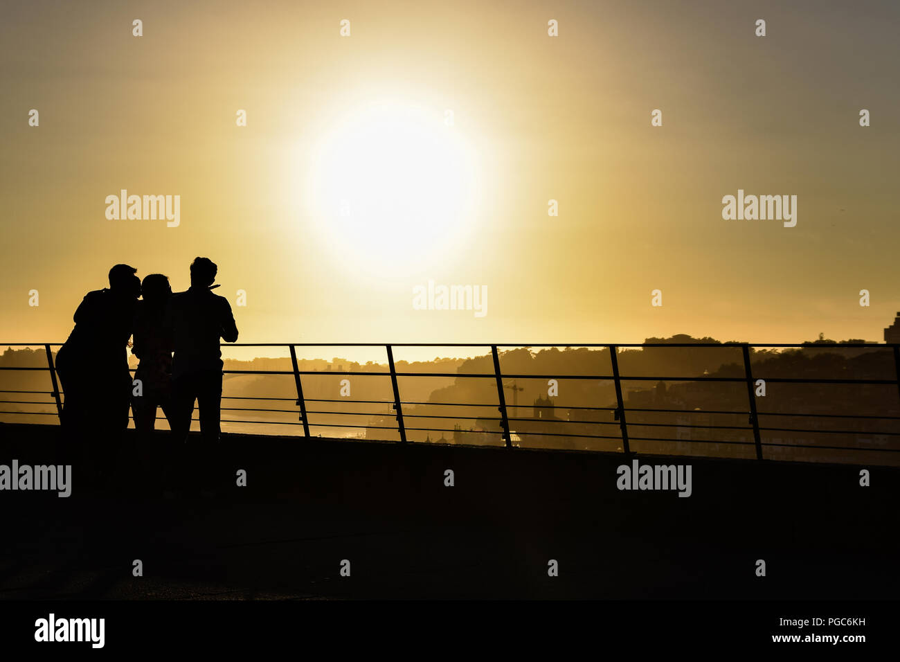 Silhouette di alcuni giovani a guardare la città di Porto al tramonto Foto Stock