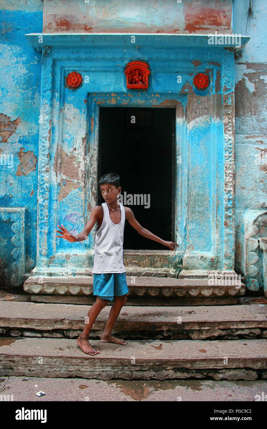 Kid sta davanti a una porta in Caranasi, India Foto Stock