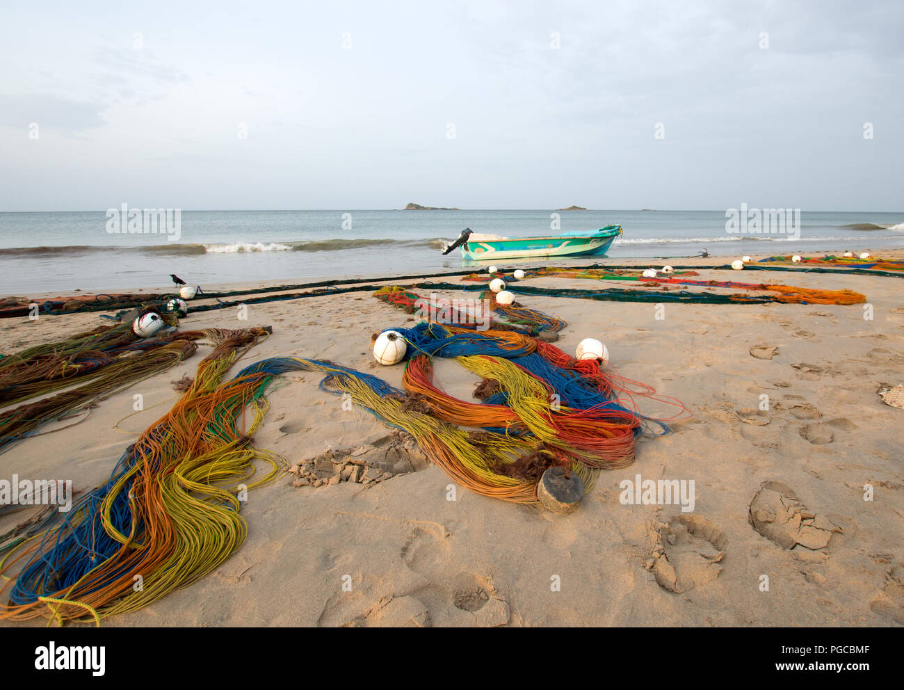 Multi-colore di reti da pesca ad asciugare al sole accanto alla piccola barca da pesca su Nilaveli Beach di Trincomalee Sri Lanka asia Foto Stock