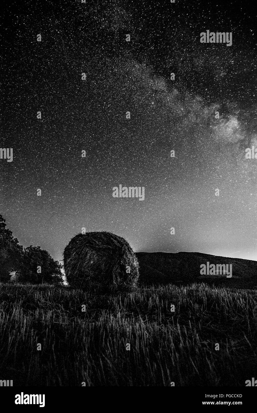 Bellissima vista starred il cielo notturno con via lattea su un campo coltivato con balle di fieno Foto Stock
