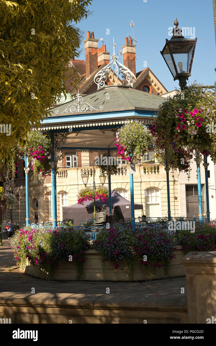 Le composizioni floreali intorno al palco per spettacoli in Carfax di Horsham Town Center. Fiori d'estate in cestelli appesi. Foto Stock