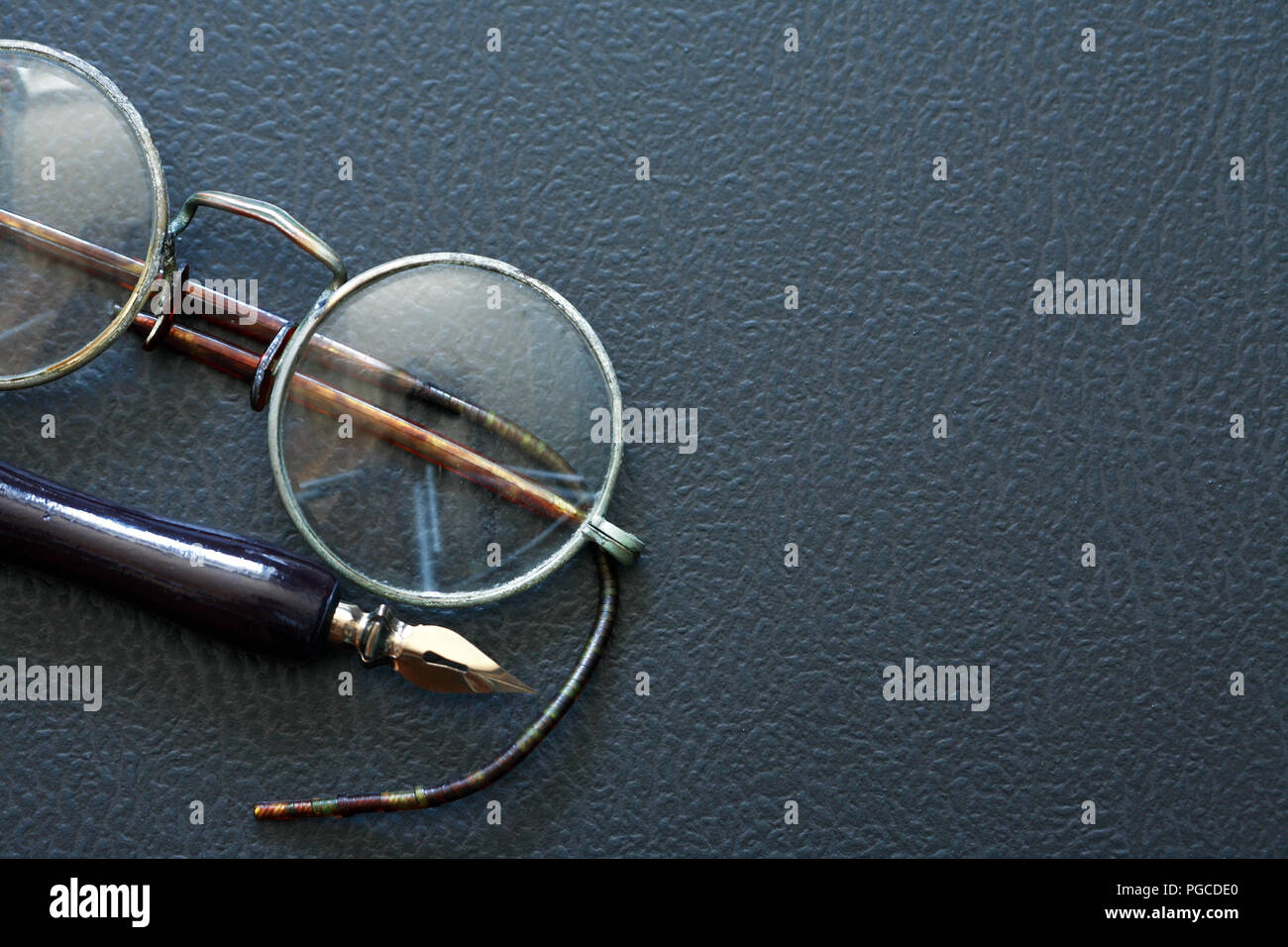 Primo piano di vecchi occhiali vicino a penna su sfondo scuro Foto Stock