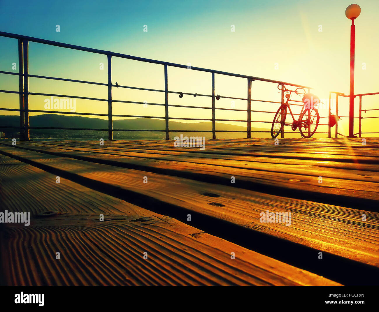 Silhouette di una bicicletta su un ponte sul mare al mattino. Golden tramonto sul mare costa. Sfondo dello stile di vita sulla spiaggia soleggiata, Nessebar, Bulgar Foto Stock
