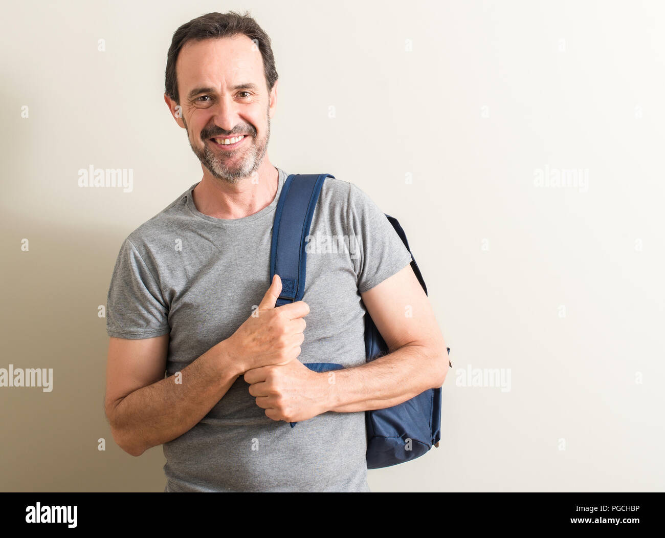 Senior uomo utilizzando uno zaino con faccia felice in piedi e sorridente  con un sorriso sicuro che mostra i denti Foto stock - Alamy