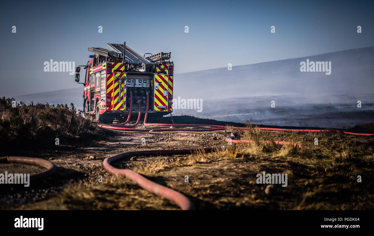 Motore Fire contro il bruciato heather & moorland come fumo porta nel vento durante la Saddleworth Moor incendi Foto Stock