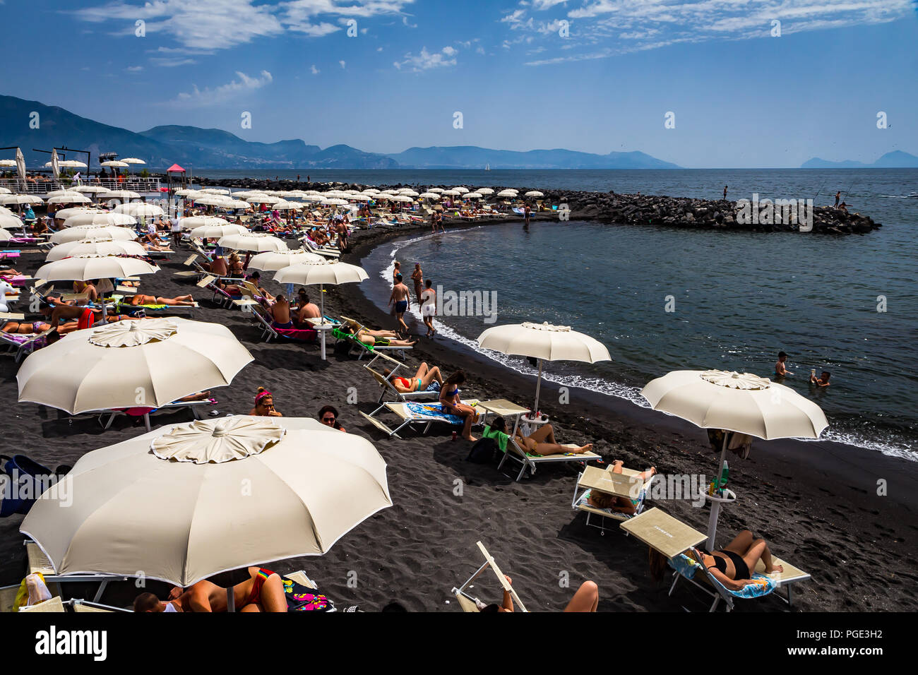 Torre del Greco, vicino napoli, Italia - 3 giugno 2018 - ombrelloni bianchi su una spiaggia di sabbia nera Foto Stock