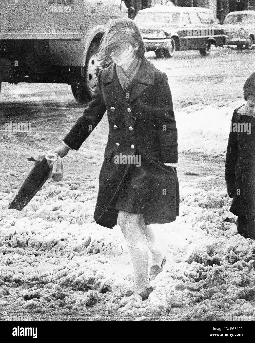 Donna Wind-Blown attraversando viscido Street Novembre 1966 Foto Stock