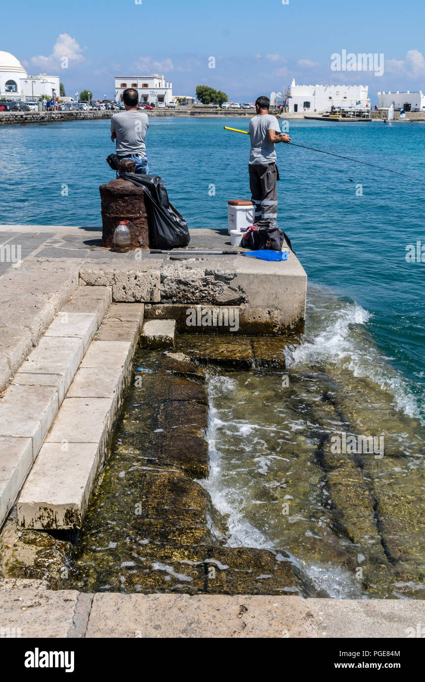 Questa è una foto di due greci fisherman pesca al largo del molo all'ingresso del porto vecchio di Rodes città. Foto Stock