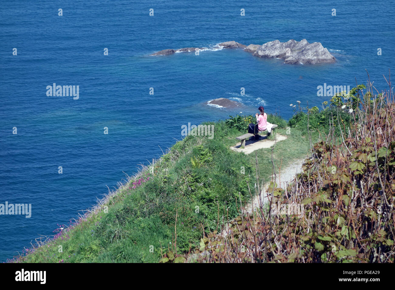 Una donna di mangiare il pranzo seduti su un banco di lavoro su sette colline Torrs Park Cliff sentiero pedonale nelle vicinanze del Ilfracombe sul sud-ovest sentiero costiero, Devon, Inghilterra, Foto Stock