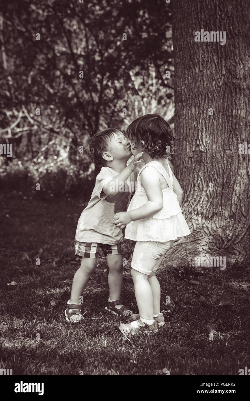 Bianco e nero ritratto di due simpatici adorabili bambini Bambini Bimbi abbracciando e baciando ogni altro amore amicizia nel concetto di infanzia, migliore amico Foto Stock