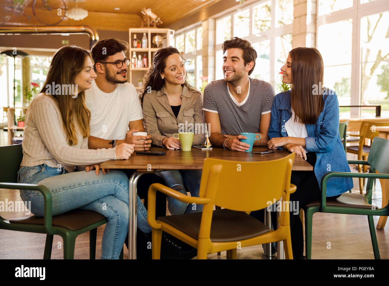 Un gruppo di amici a parlare e a bere caffè presso la caffetteria Foto Stock