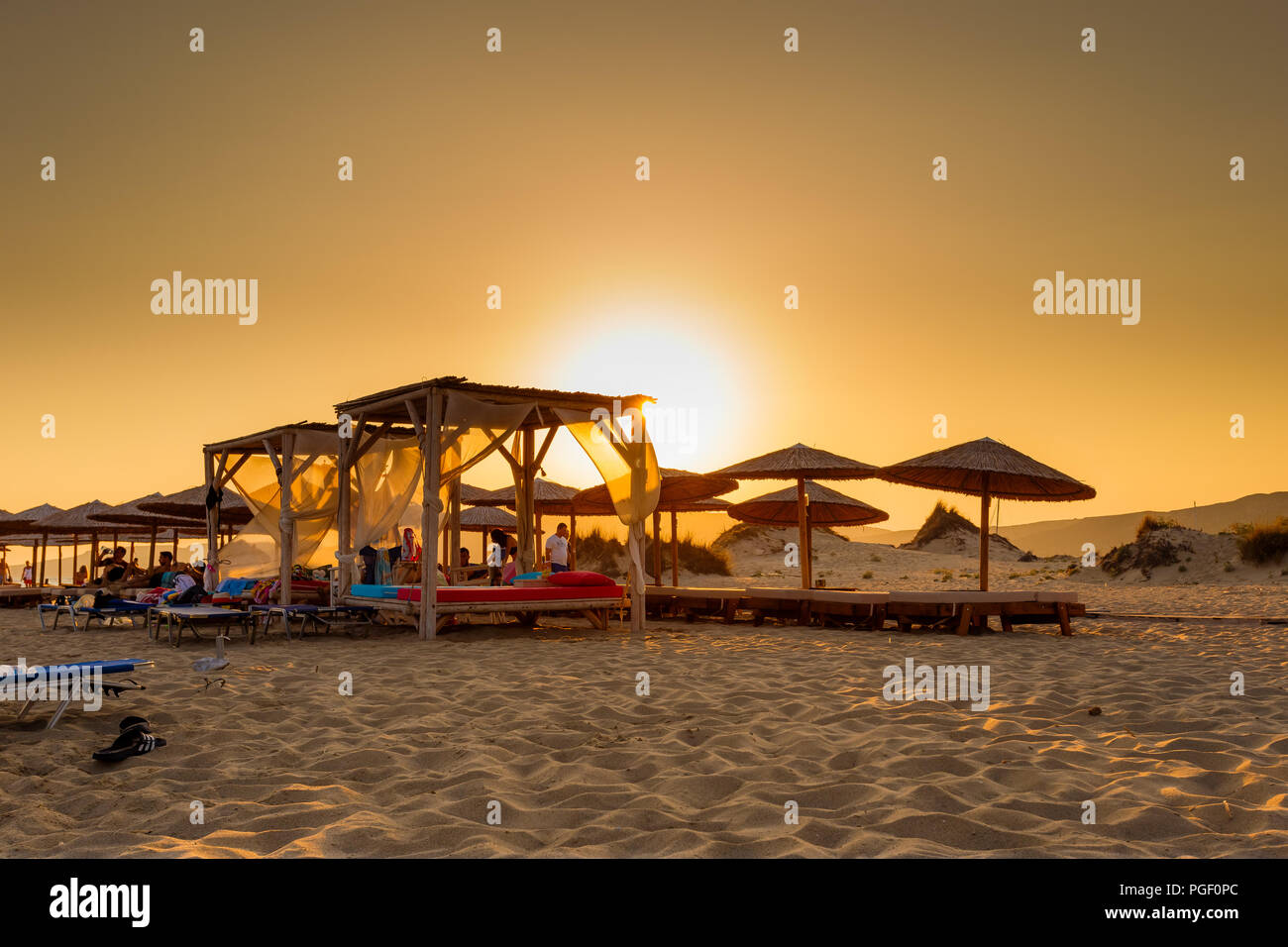 Linee di lettini in spiaggia Simos in Elafonisos isola in Grecia contro una calda estate tramonto Foto Stock