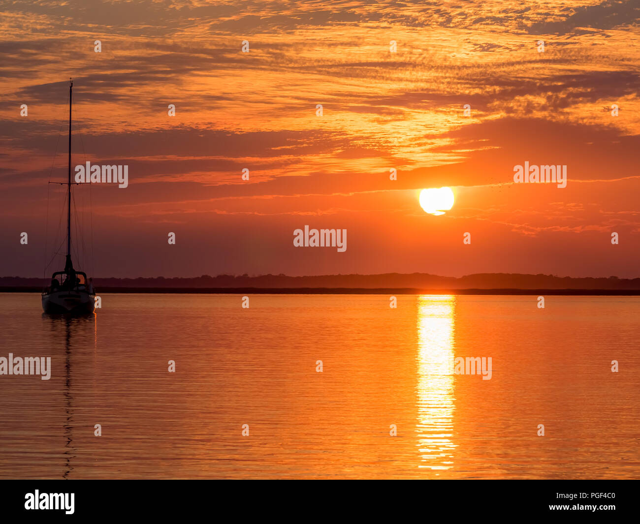 Una barca a vela ormeggiata per la notte su di una tranquilla e serena notte al tramonto. Foto Stock