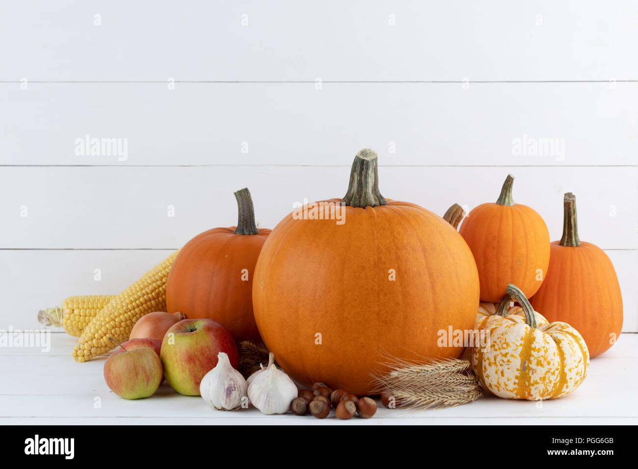 Autumn harvest ancora in vita con zucche, spighe di grano, nocciole, aglio e cipolla e bacche di rosa canina su sfondo di legno Foto Stock