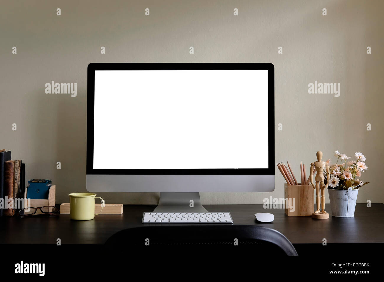 Il display del computer e gli strumenti di office su tavola nera. Computer desktop isolato sullo schermo. Moderna area di lavoro creativo con fiore . Vista frontale. Foto Stock
