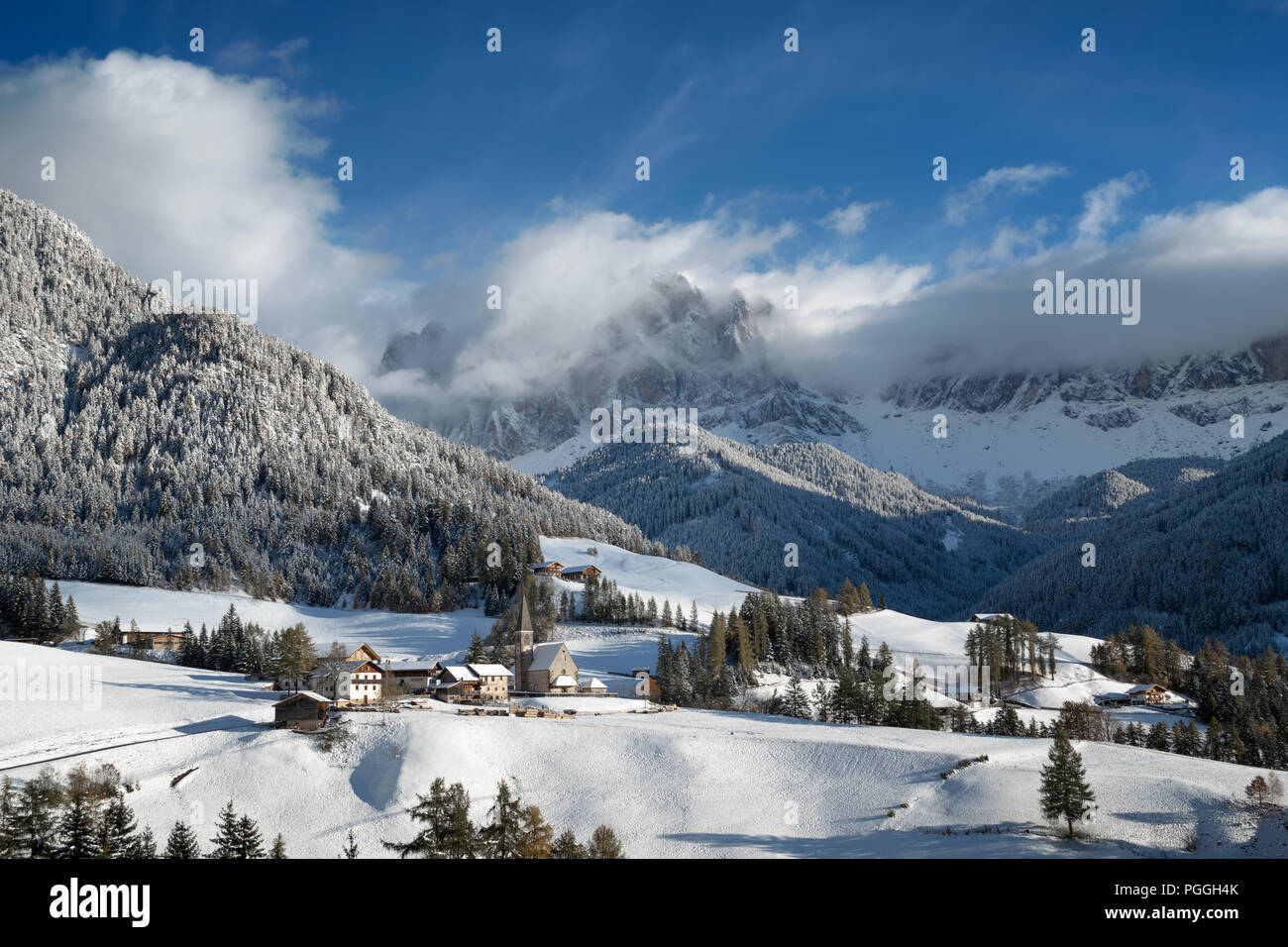 La chiesa nel piccolo villaggio di Santa Maddalena in neve fresca con sullo sfondo le Odle Dolomiti picchi di montagna in inverno, Italia. Foto Stock