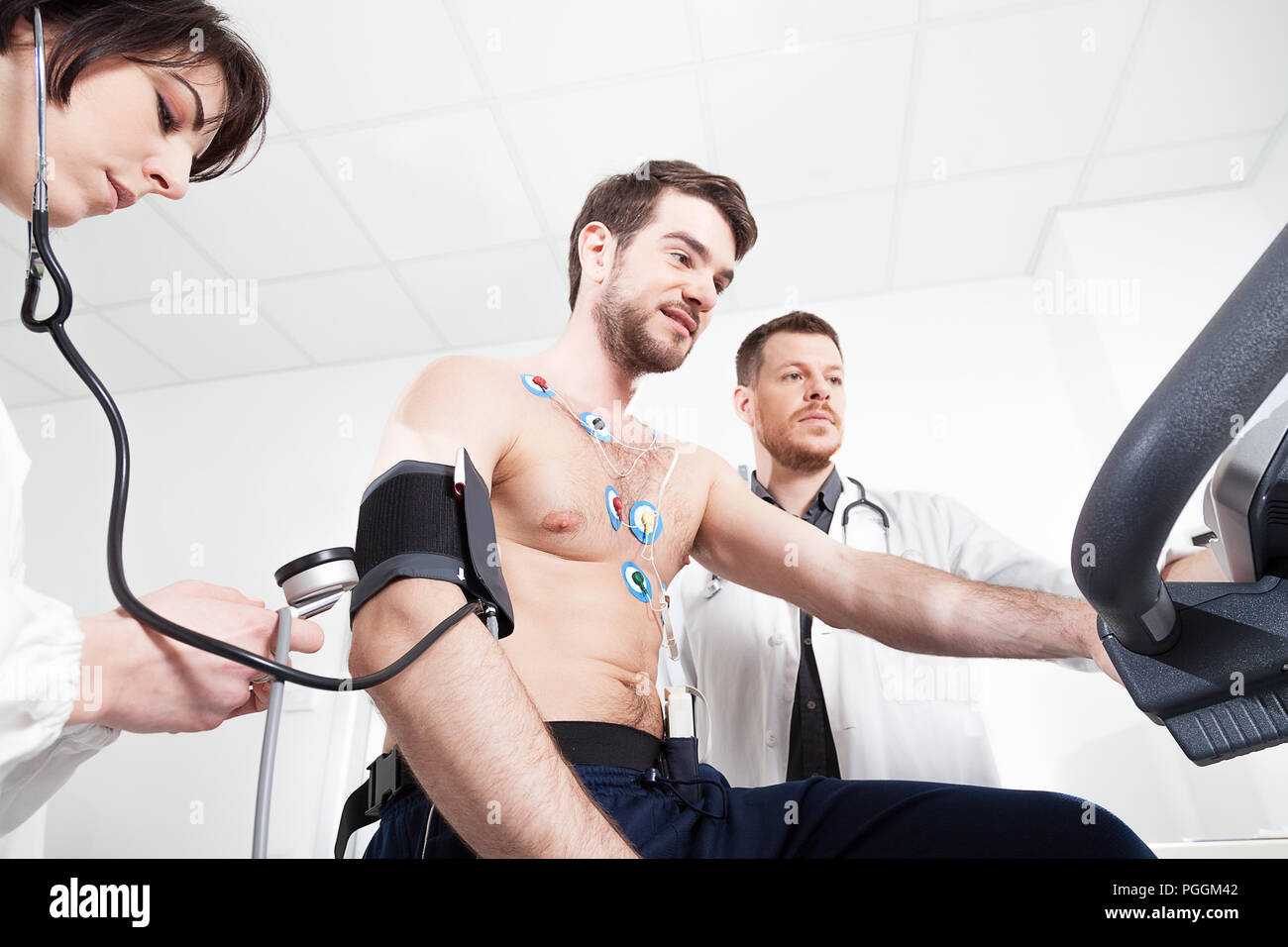 Medico e infermiere assistere il paziente durante la visita medica di stress cardiaco test Foto Stock