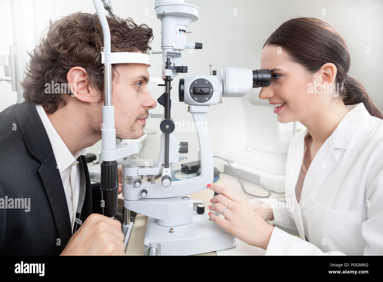 Un uomo avente un occhio test con lampada a fessura / medico donna in Oftalmologia Clinica facendo retina cornea diagnostica esame con la visione del paziente dalla moderna c Foto Stock