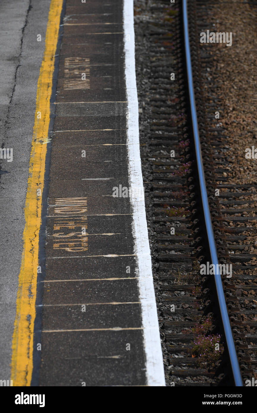 Mente il passo avvertenze su una stazione ferroviaria piattaforma guardando dall'alto. Foto Stock