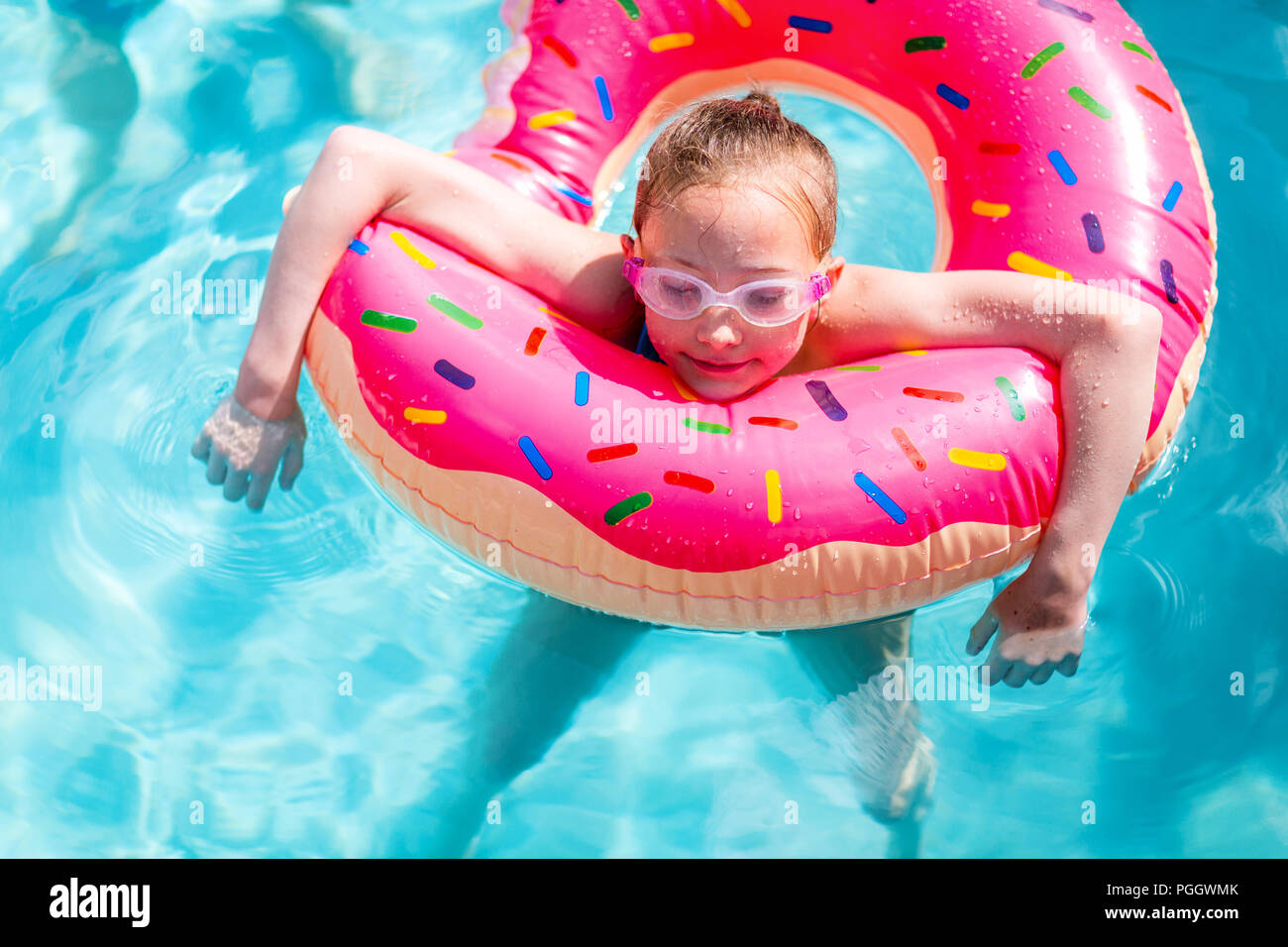 Adorabile ragazza con rosa anello gonfiabile nuoto in una piscina su vacanze estive Foto Stock