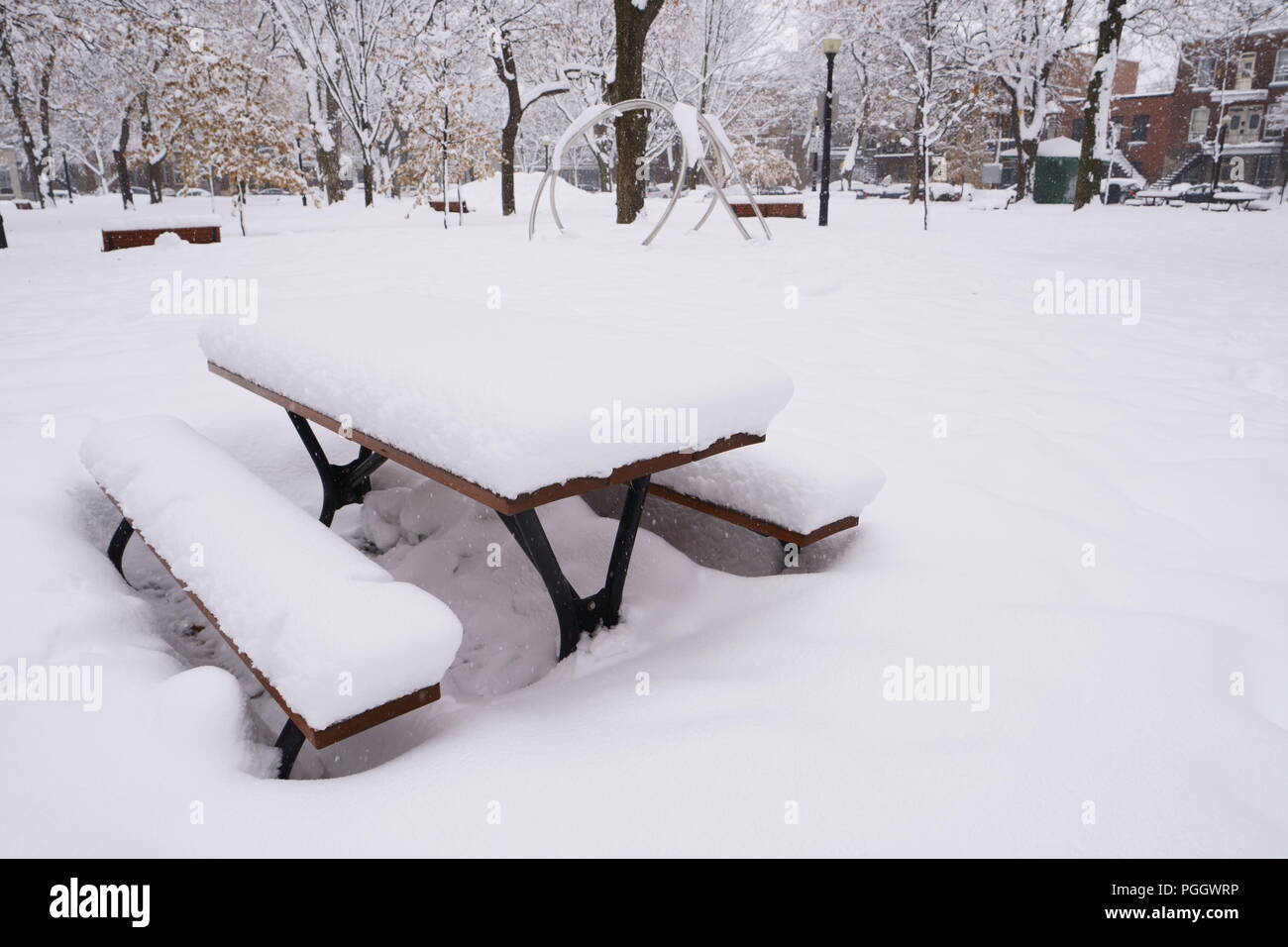 La prima neve è caduta su tutto durante la notte. Un tavolo da picnic è coperto di neve in un parco pubblico. Foto Stock