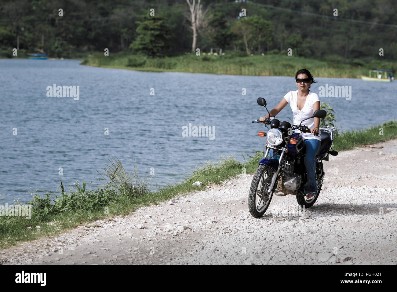 Donna che guida motocicletta senza casco a Livingston, Guatemala Foto Stock