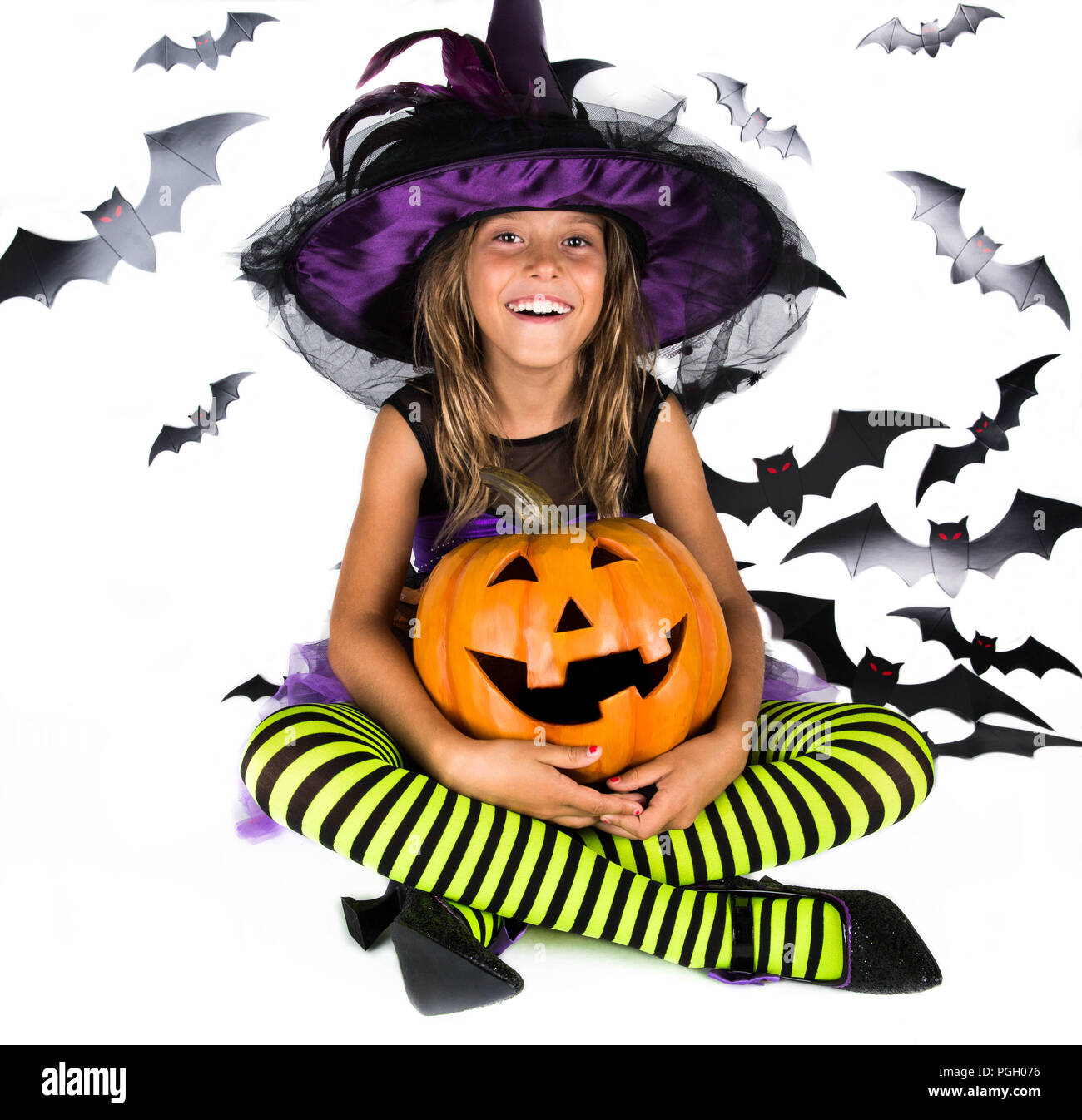 Happy halloween strega & felice di zucca. Bambina con un costume di halloween di una strega con cappello, striped gambe tenendo due smiley zucche di Halloween Foto Stock
