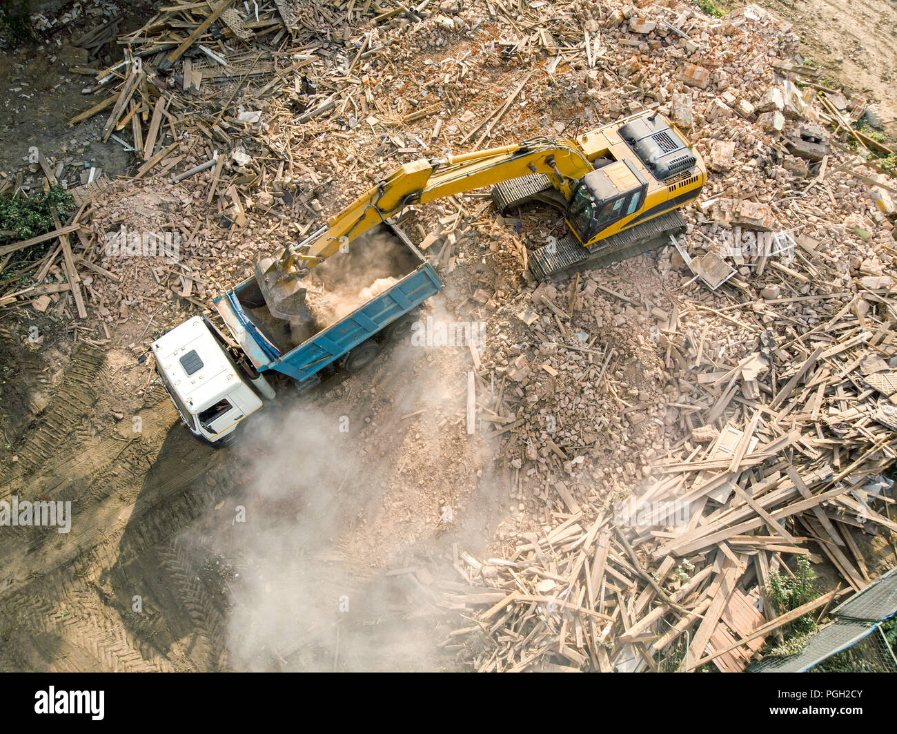 Escavatore cingolato detriti di caricamento di un edificio distrutto nel carrello. vista aerea del sito di demolizione Foto Stock