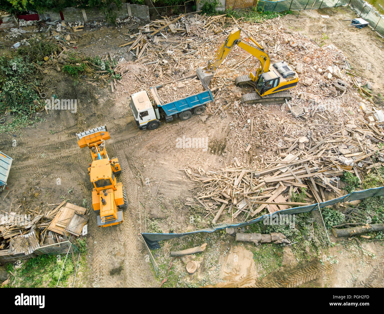 Vista aerea di macchinari pesanti costruzione. escavatore carico di un autocarro con pianale di scarico dopo la demolizione di casa Foto Stock