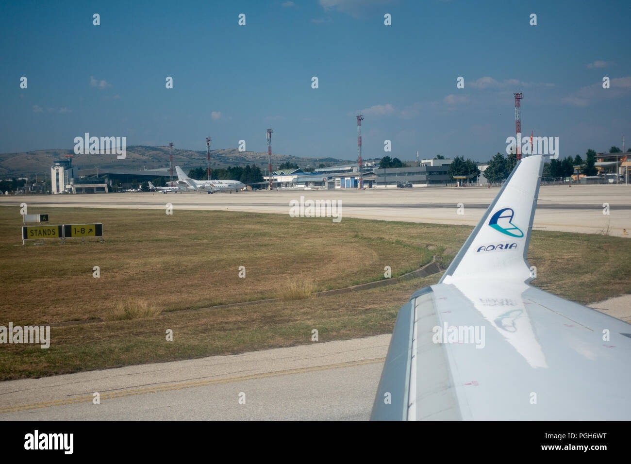 Skopje, Macedonia - 25 agosto 2018: vista attraverso la finestra aereo sul parafango del velivolo, Adria Airways logo sulla punta ala e Skopje airport Foto Stock