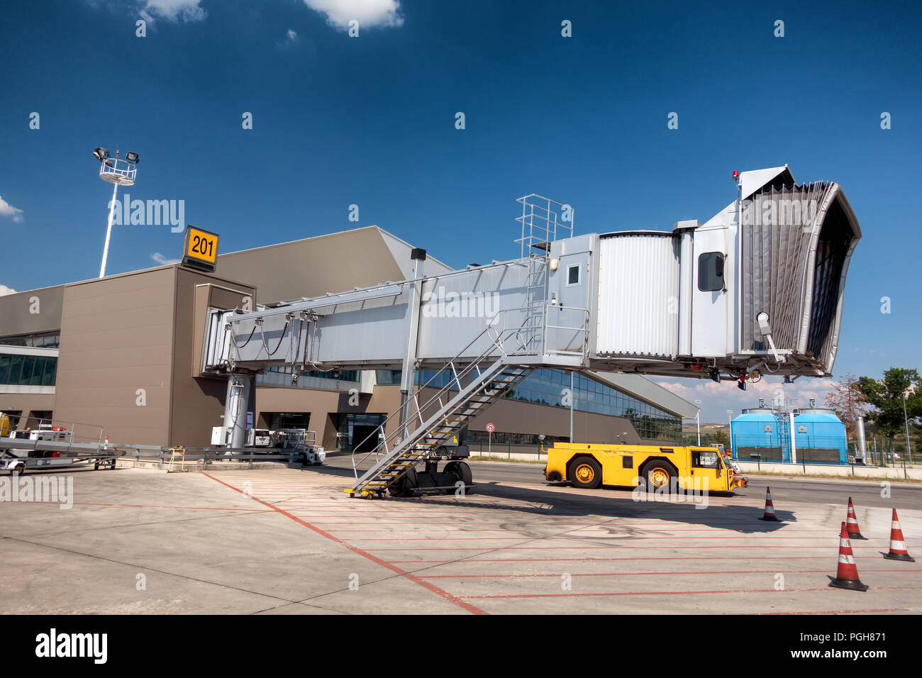 Aero passerella ponte, ponte di imbarco in aeroporto con il giallo rimorchiare il trattore al di sotto di Foto Stock