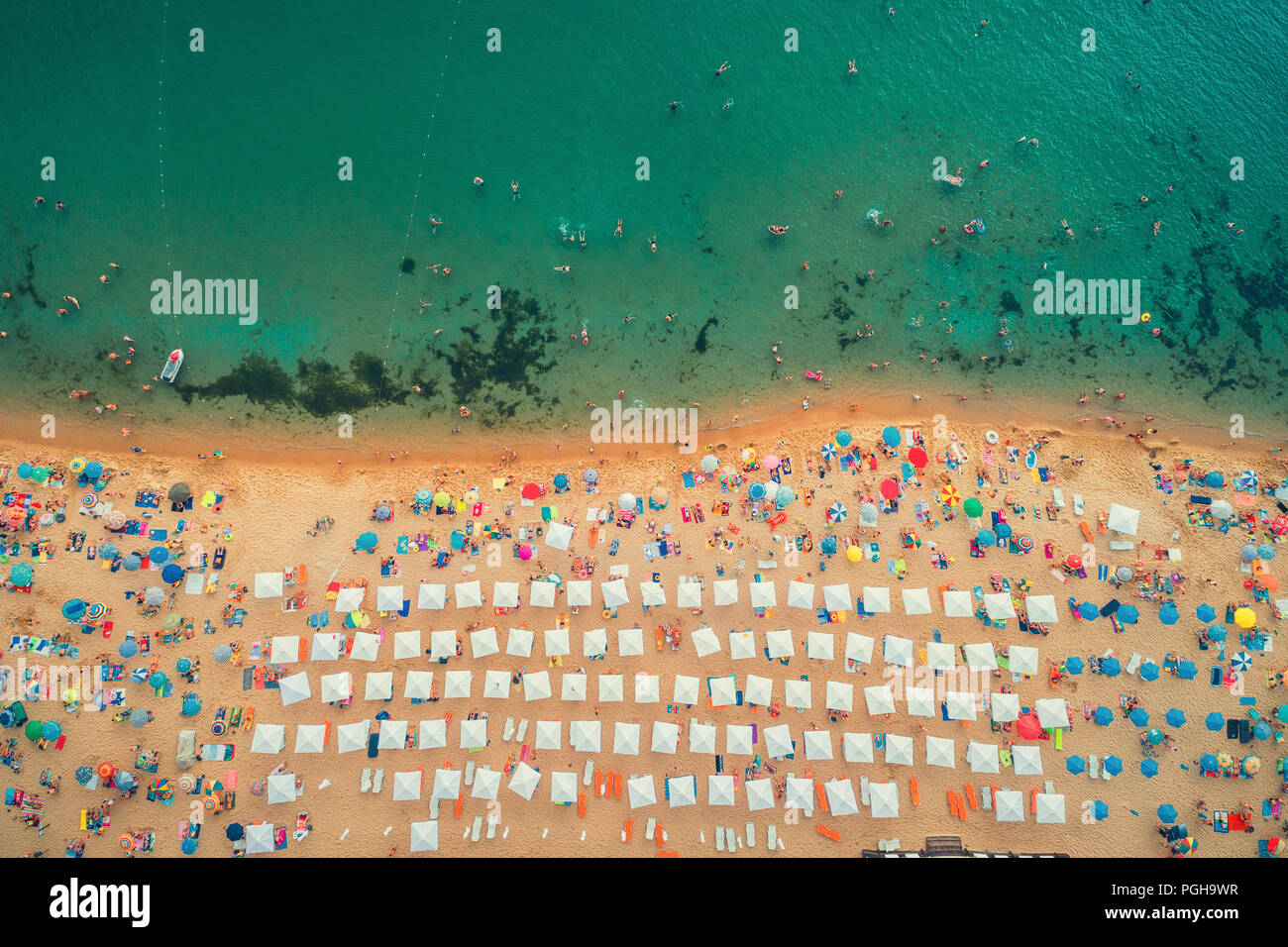 Antenna vista superiore sulla spiaggia. Persone, ombrelli, la sabbia e le onde del mare Foto Stock