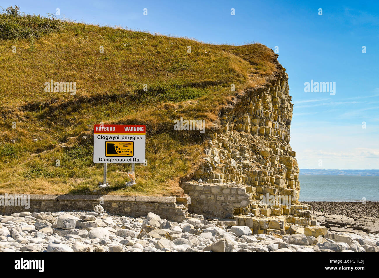 Vista del paesaggio di un segno a fianco di scogliere di visitatori di avvertimento alla spiaggia di Llantwit Major del rischio di caduta di sassi. Foto Stock