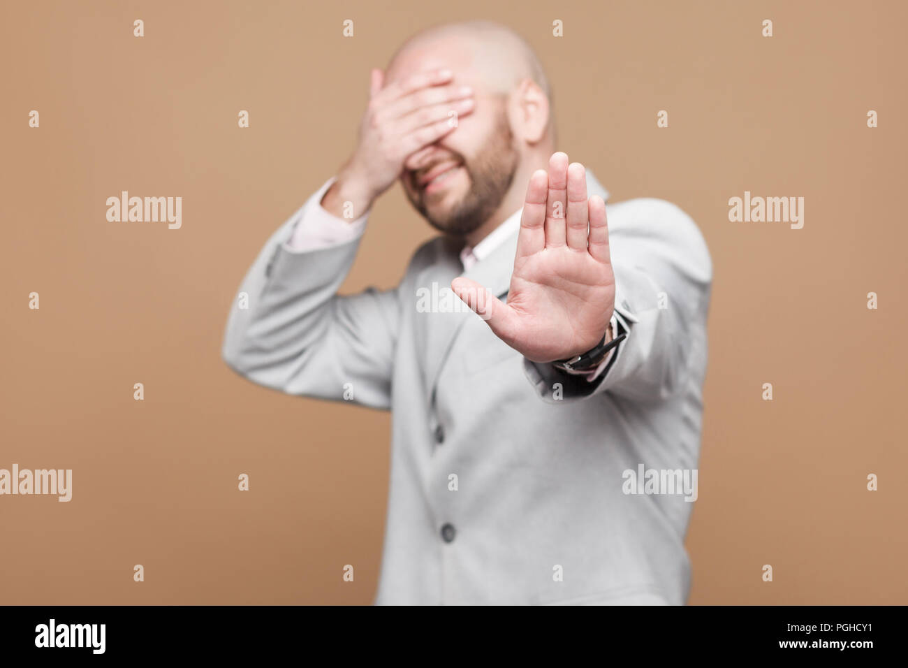 Fermare, non voglio vedere. Ritratto di confusa di mezza età barbuto calva imprenditore della luce classico abito grigio in piedi con gesto di arresto, coperchio Foto Stock