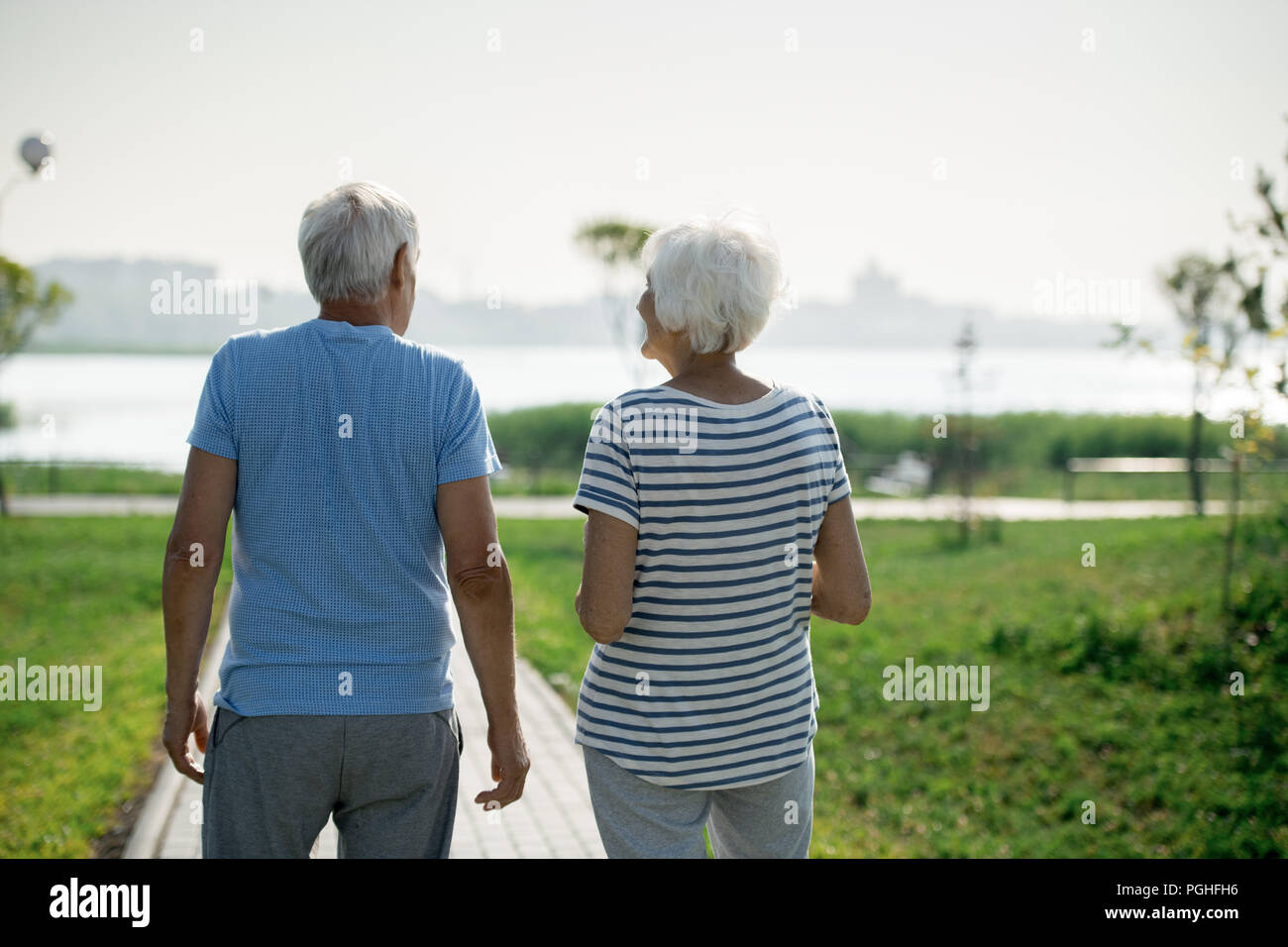 Vista posteriore ritratto di active coppia senior a piedi su Park Lane lungo la riva del mare all'aperto , spazio di copia Foto Stock