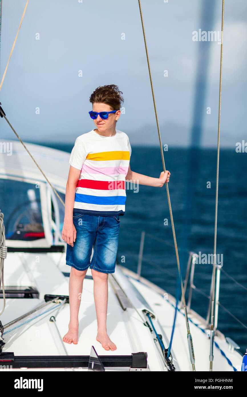 Ragazzo adolescente godendo di vela a bordo di un catamarano di charter o yacht Foto Stock