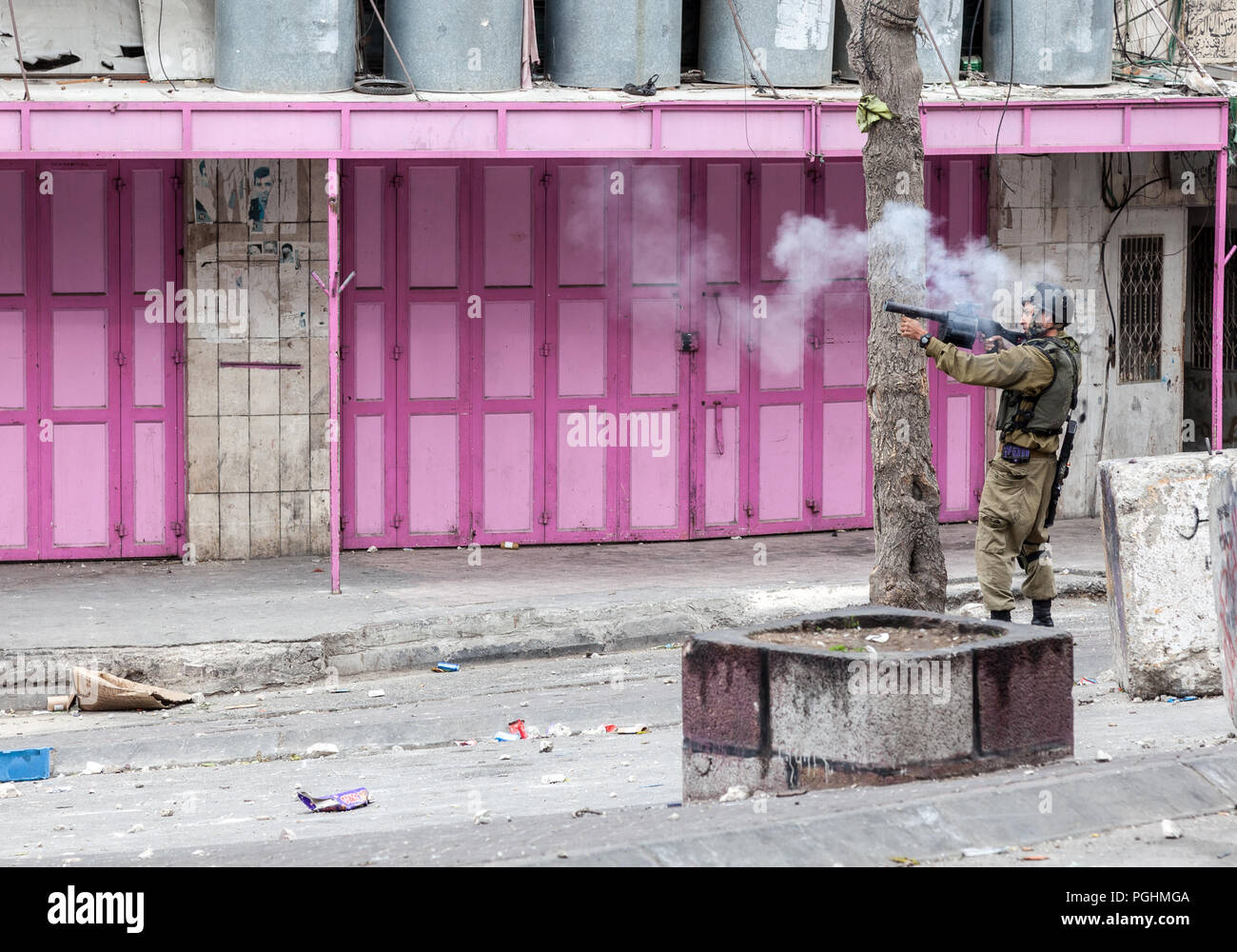 Hebron, Palestina, Novembre 29, 2013: Forze di Difesa Israeliane soldato è la ripresa di una granata di gas per disperdere i giovani palestinesi uomo durante disordini a Hebron Foto Stock