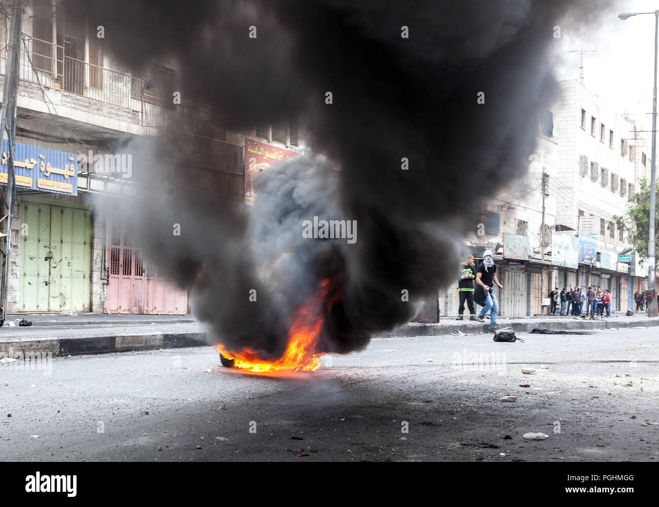 Hebron, Palestina, Novembre 29, 2013: giovani palestinesi si nascondono dietro il fumo di combustione pneumatico durante disordini a Hebron sulla città vecchia Foto Stock