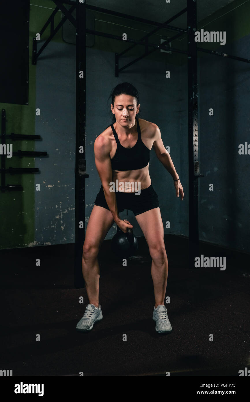 Ragazza muscolare in palestra facendo un jerk dumbbell Foto Stock