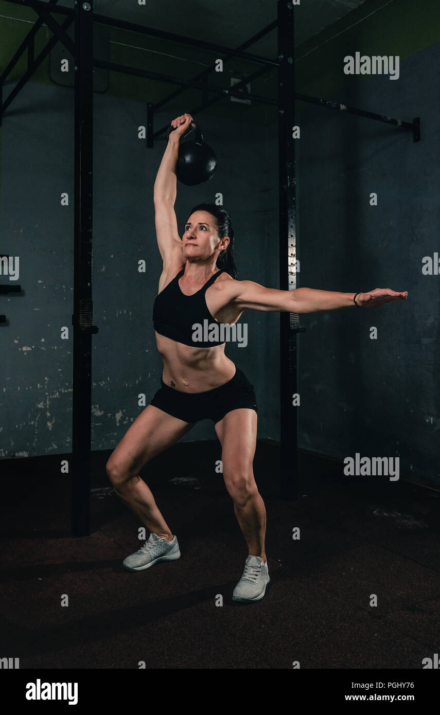 Ragazza muscolare in palestra facendo un jerk dumbbell Foto Stock