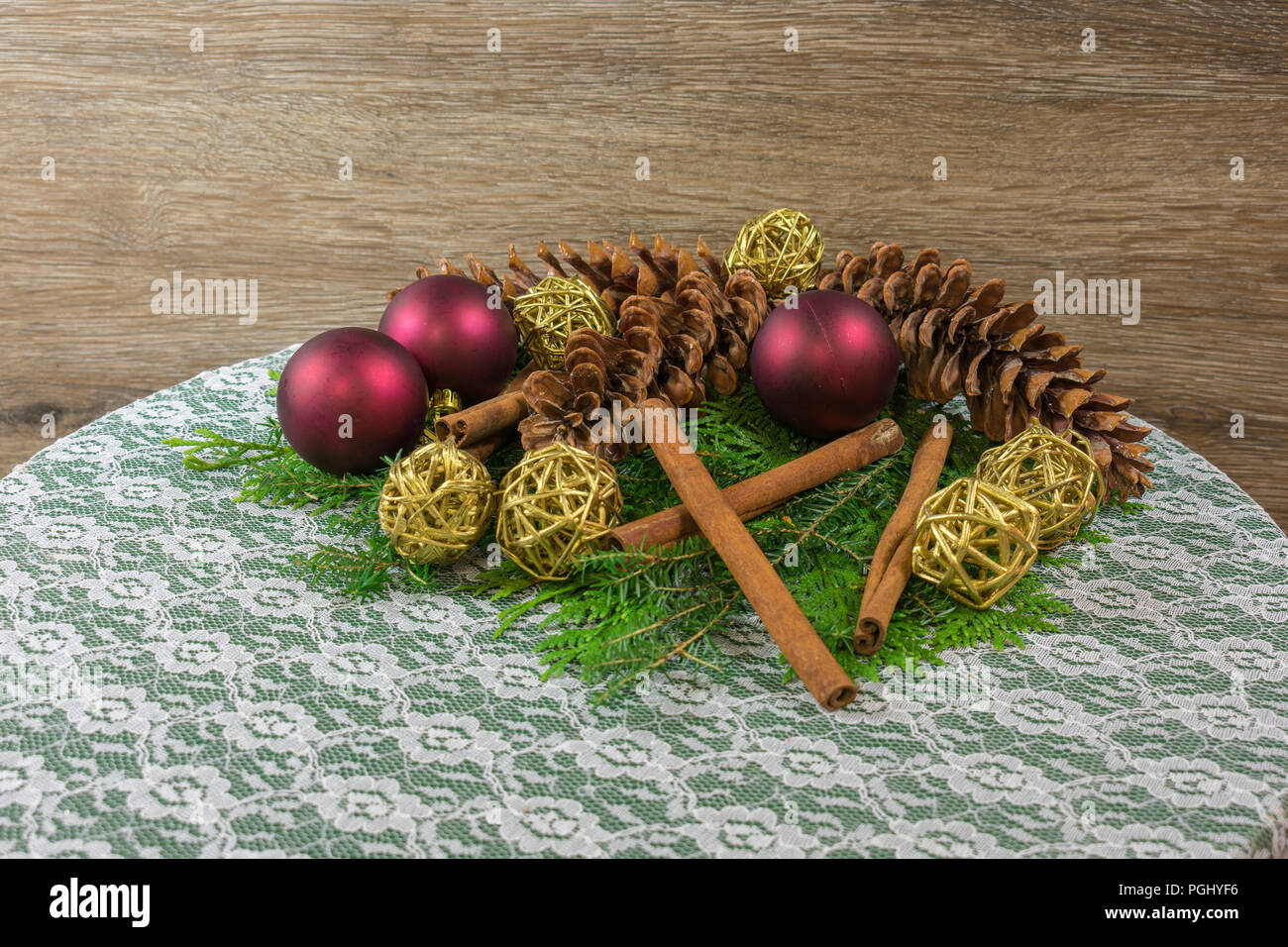 Tre bianchi pigne su un letto di cedro e balsamo ramificato, con sei d'oro ramoscello sfere, tre rossi ornamenti e cinque stecche di cannella Foto Stock