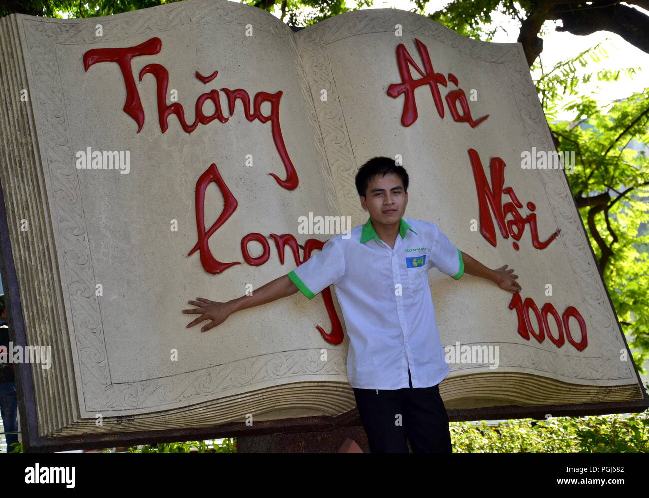 Un ragazzo si pone con una gigantesca scultura del libro, che celebra il 1000th anniversario della fondazione di Hanoi, accanto al lago Hoan Kiem, Hanoi, Vietnam. Foto Stock