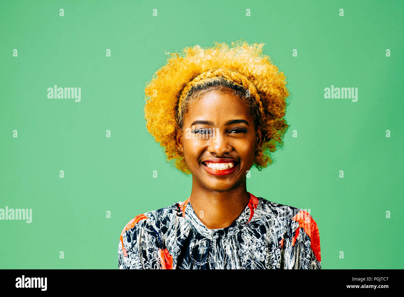 Un felice ragazza giovane con un grande sorriso e di fronte a uno sfondo verde Foto Stock